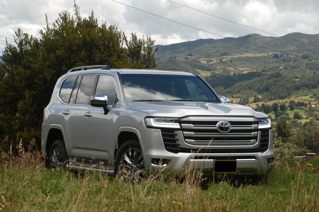 Silver Toyota Land Cruiser, one of the best armoured SUVs in Pakistan, parked on a grassy hill with mountains in the background.