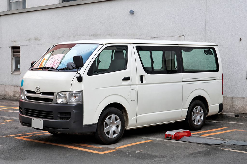 White Toyota Hiace van parked in an urban security transport setting, representing bulletproof van and armoured group transport solutions by AAT ArmourTech Islamabad Pakistan